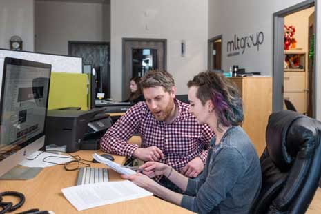 two people sitting at computer reviewing notes